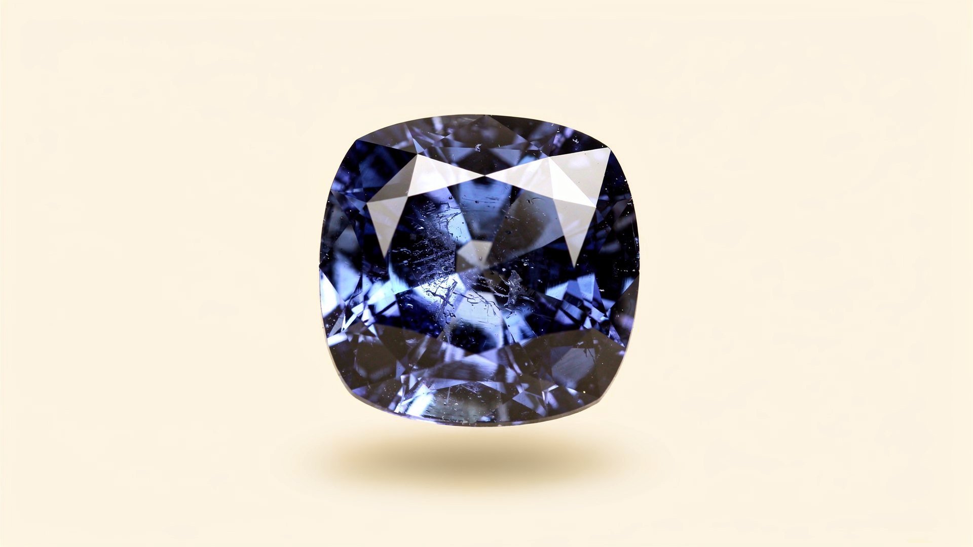 A large cushion cut blue sapphire on a cream ground