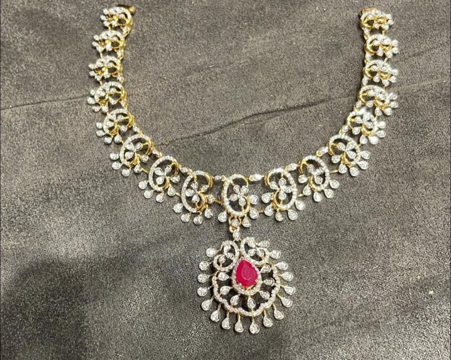 Gold necklace with diamond scrollwork and a ruby drop